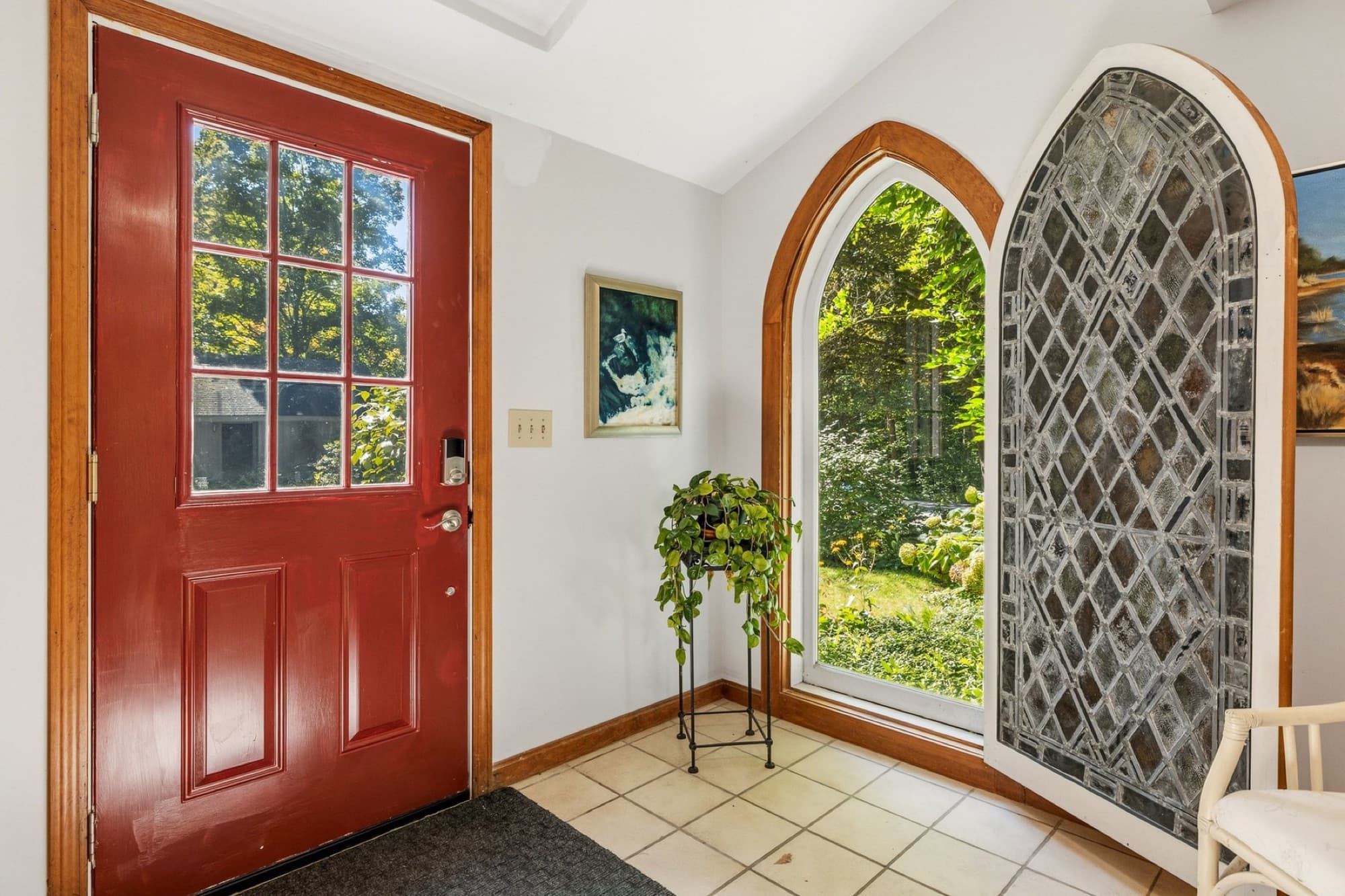 The red front door beside the leaded-glass Gothic window, with a tile floor