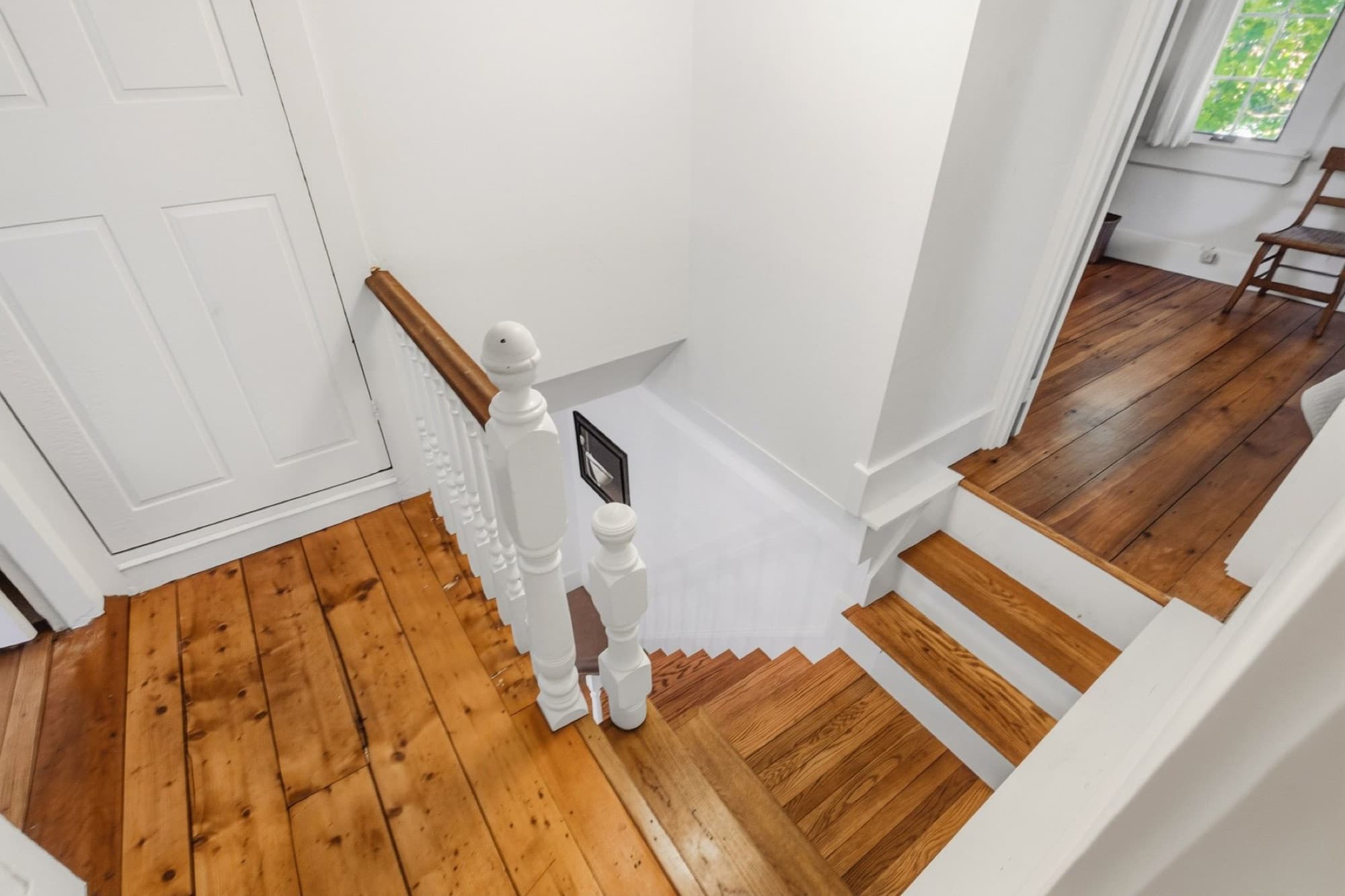 The upstairs landing with wide-plank floors and the stair rail